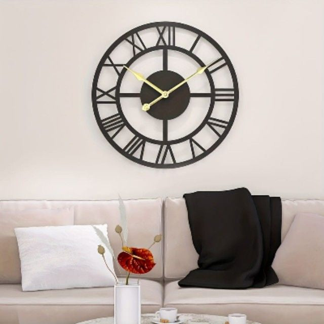 Large wall clock with Roman numerals on a white wall above a beige sofa.