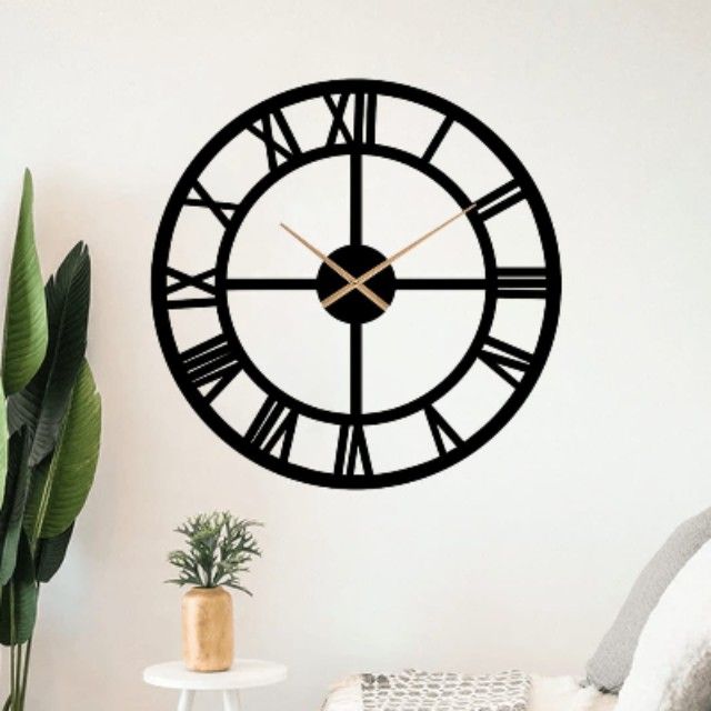 Large black wall clock with Roman numeral design on a white wall.