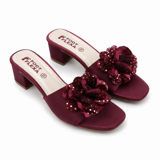 A pair of women's heeled mule sandals in deep burgundy, featuring a wide strap embellished with large fabric flowers and sparkling sequins, set against a plain white background.