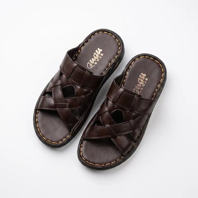 A pair of dark brown leather slide sandals with woven crisscross straps and contrast stitching, displayed on a clean white background. The brand name 'CAGIA' is visible on the footbed.