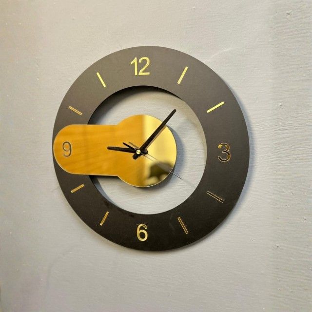 Wall clock with gold hand and black casing on a light gray background