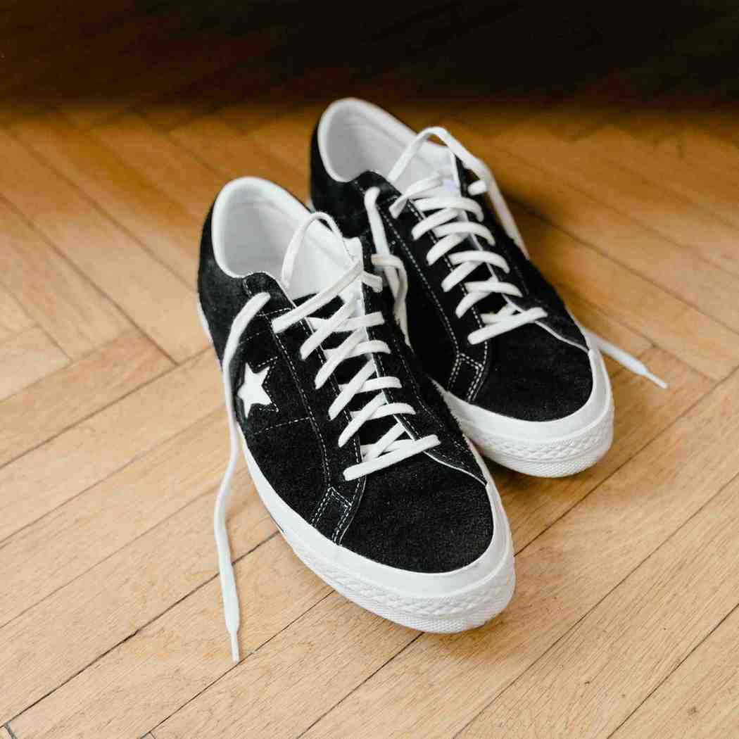 Black sneakers with white laces on a wooden floor