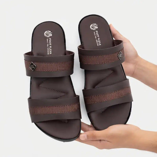 A pair of dark brown slide sandals with textured woven straps, held by two hands against a light gray background. The insoles show the brand name 'FOOT REA'.